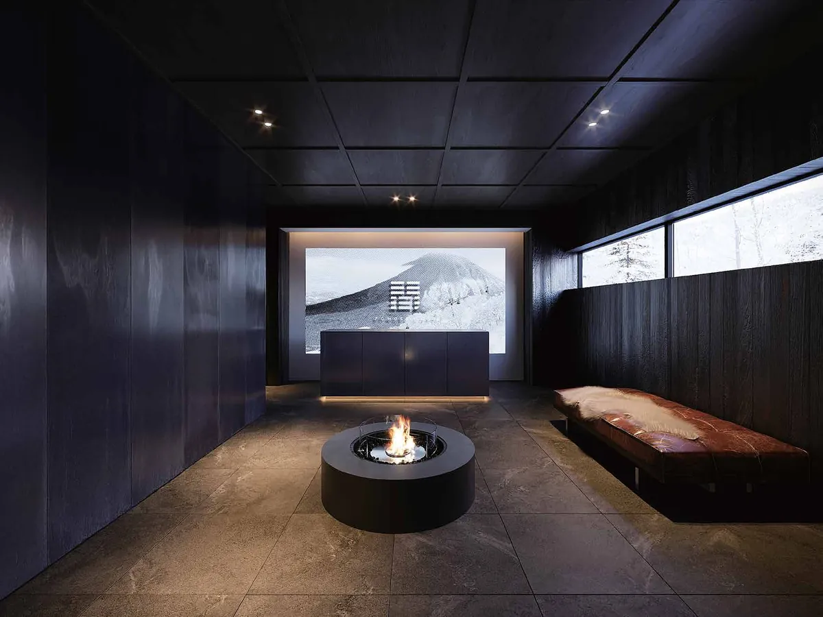 Entrance lobby with a round fire pit, timber panelling and a framed view of Mt. Yotei