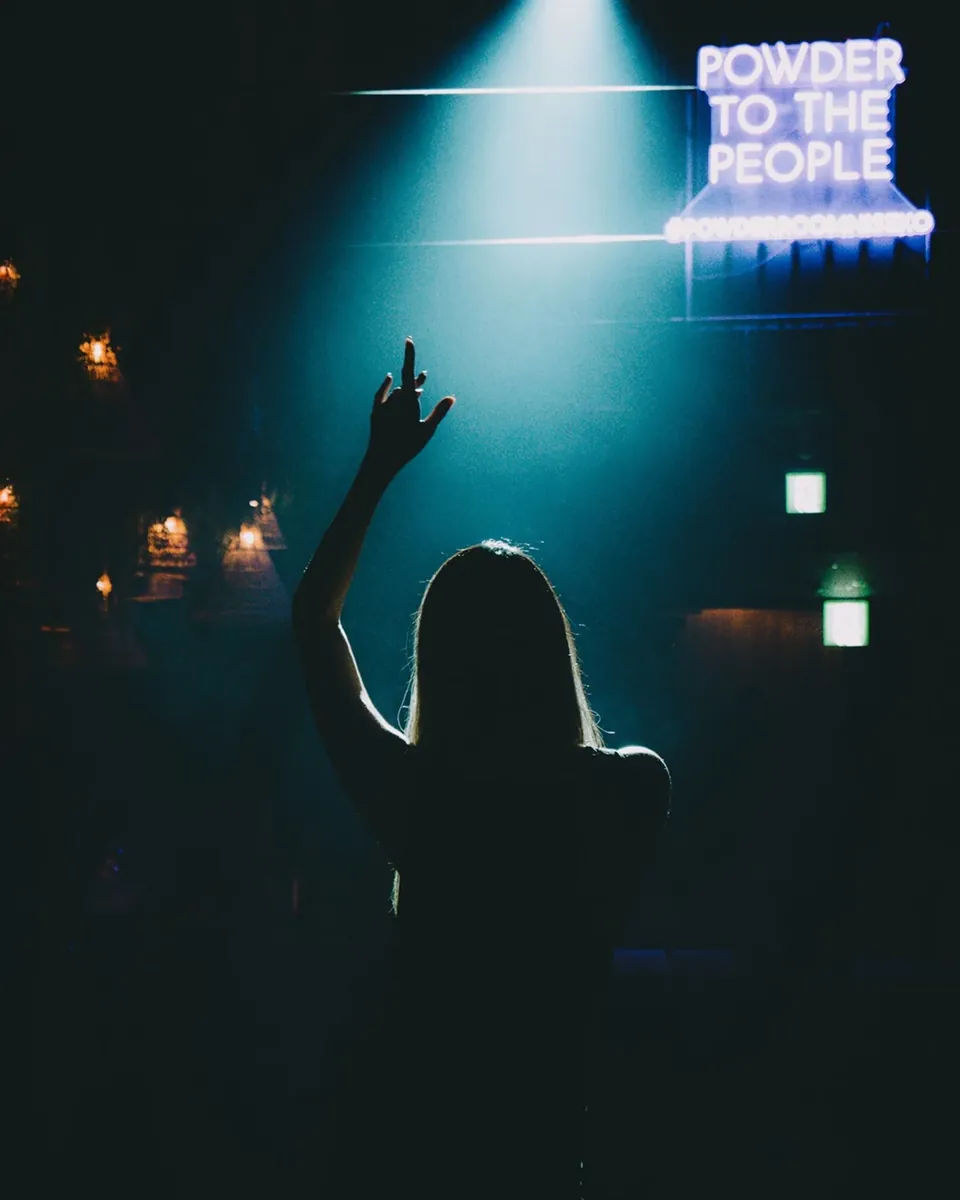 Neon sign reading Powder to the People above a crowd at Powder Room Niseko